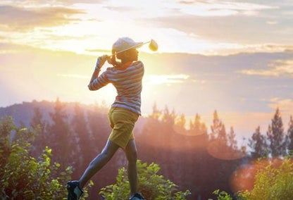 Person golfing in the sun with a mountaintop in the back